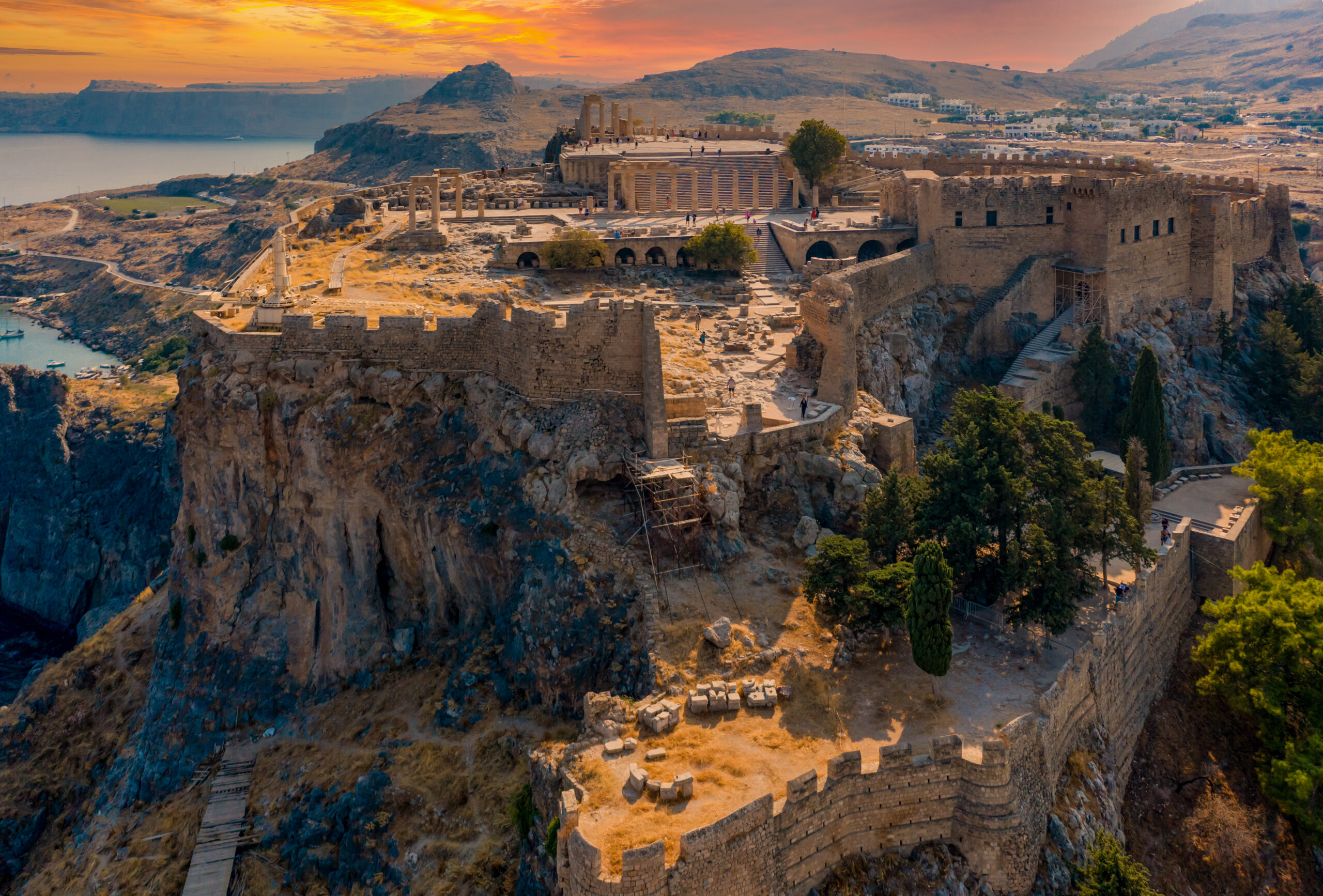 Aerial drone photo of famous beach of Lindos with turquoise waters and iconic ancient Acropolis - village of Lindos, Rodos island, Aegean, Dodecanese, Greece